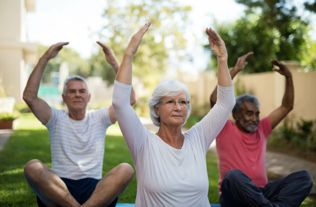 A group of older adults participating in a yoga class outdoors in their independent living community
