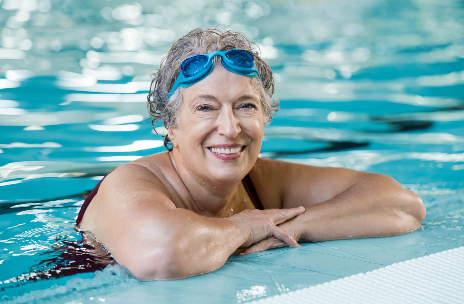 An older adult woman having a dip in the personal care home swimming pool.