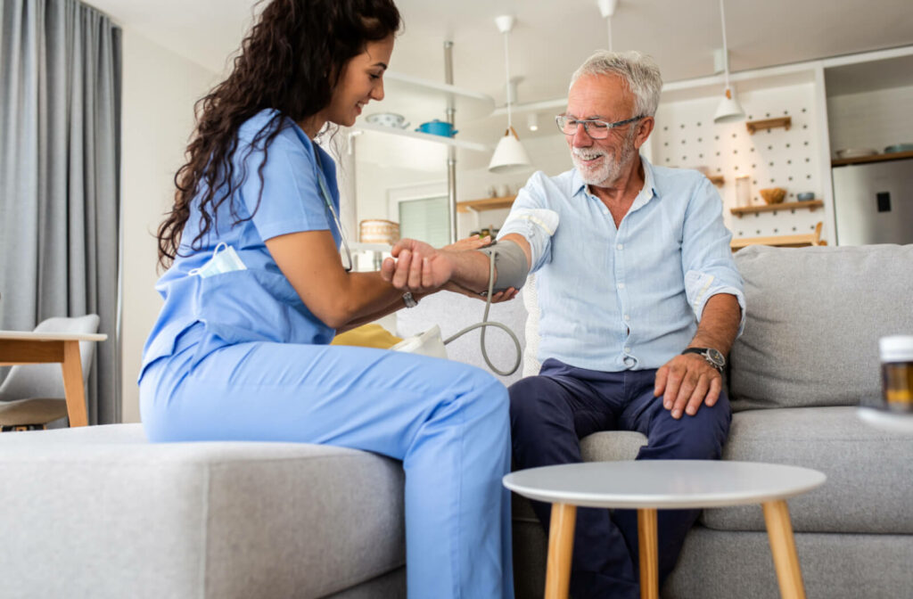 An older adult man having his blood pressure checked by a personal care home staff.